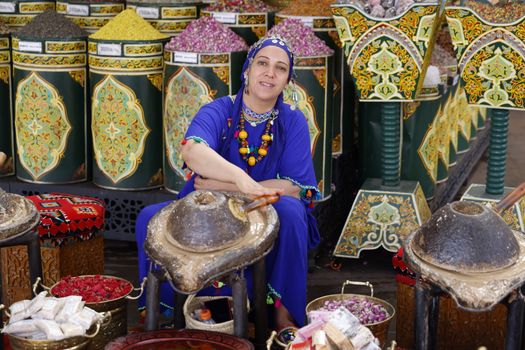 Triple Room A Moroccan woman selling spices in a traditional bazaar, showcasing vibrant culture and colors.