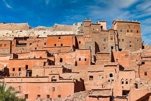 Triple Room Capture of the ancient Ait Benhaddou Kasbah in Morocco with its distinctive earthen clay architecture against a clear blue sky.